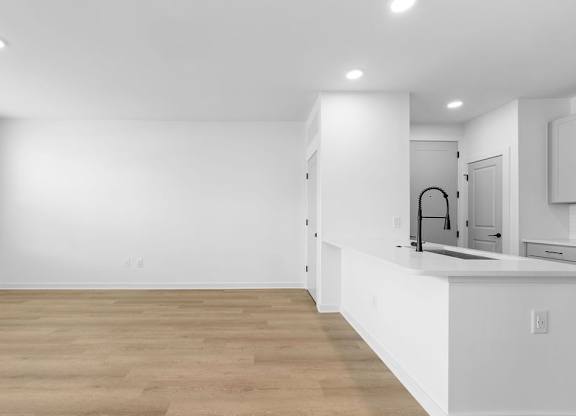 A kitchen with white cabinets and a wooden floor.