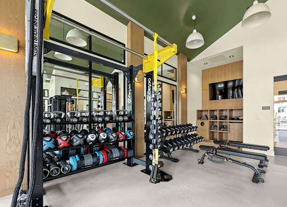 A gym with a variety of equipment including dumbbells and weight machines.