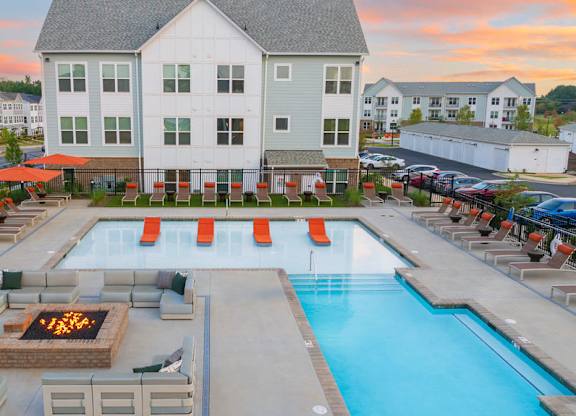 A large white building with a pool in front of it.