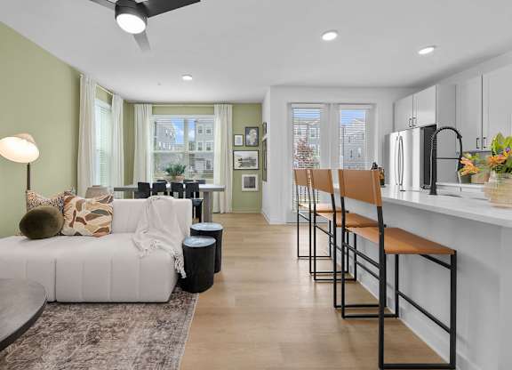 A modern living room with a white couch and a kitchen area in the background.