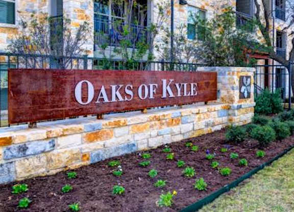A sign that says "Oaks of Kyle" is on a wall.