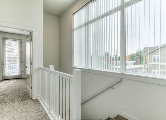A white room with a carpeted floor and a staircase with white railings.