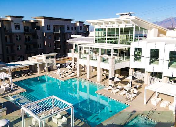 A large swimming pool surrounded by lounge chairs and umbrellas.