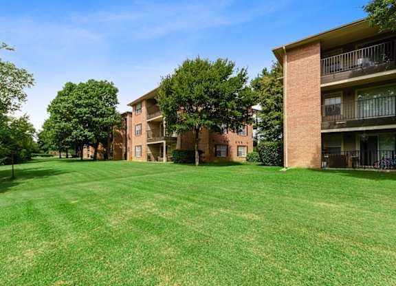 A large grassy area in front of a brick building with balconies.