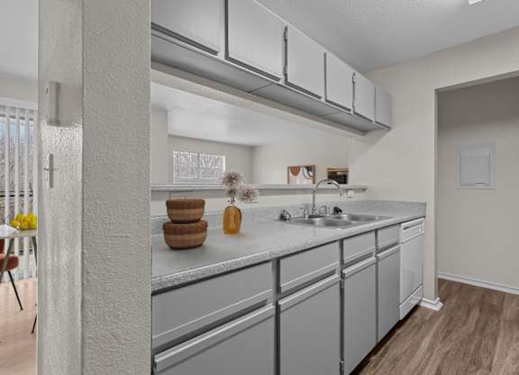 A kitchen with a white counter top and grey cabinets.
