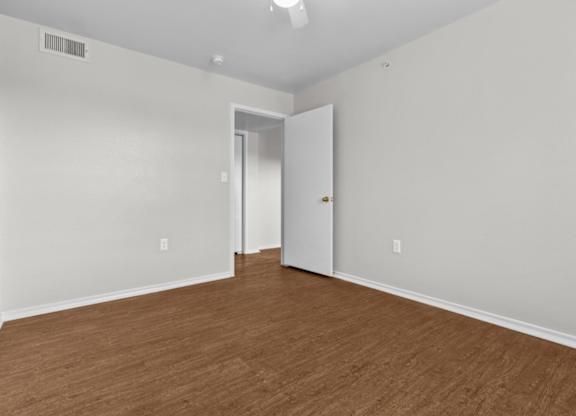 A room with a white door and a brown floor.