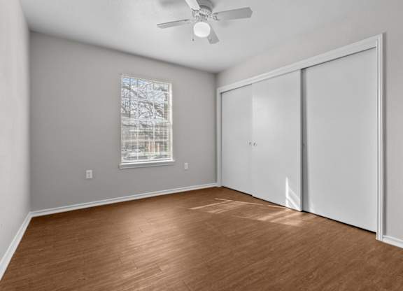 A room with a ceiling fan and a window with blinds.