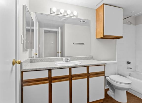 A white bathroom with a toilet, sink, and mirror.