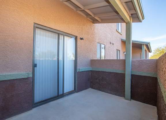 A patio with a sliding glass door and a concrete floor.