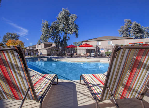 Two striped chairs are facing a pool.