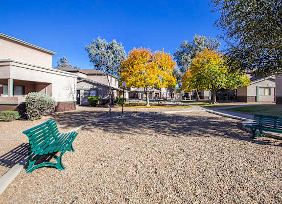 A park with benches and trees in front of apartment buildings.