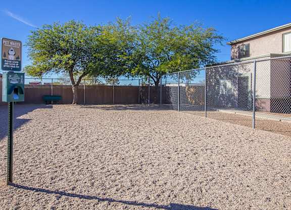A sandy area with a fence and a sign that says "Pet Mutt".