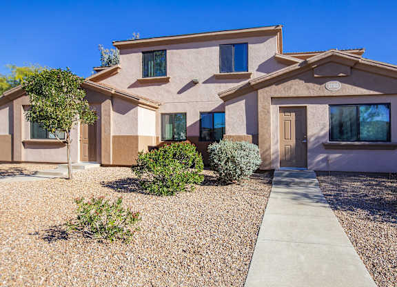 A house with a brown and beige exterior and a gravel driveway.