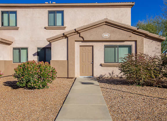 A beige house with a brown door and windows.