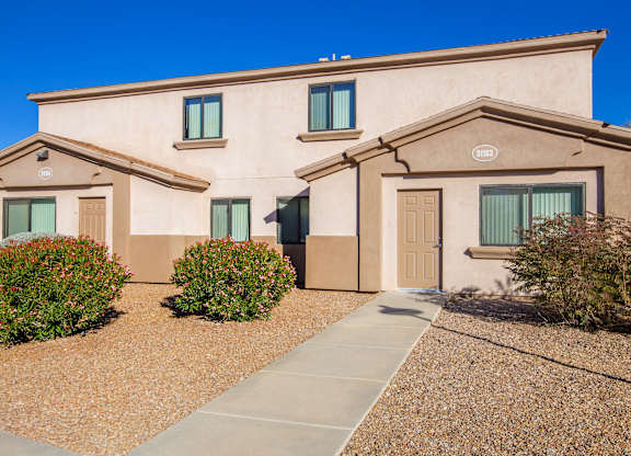 A beige house with a brown roof and a brown walkway in front.