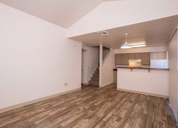 A room with wooden flooring and a staircase leading to another room.