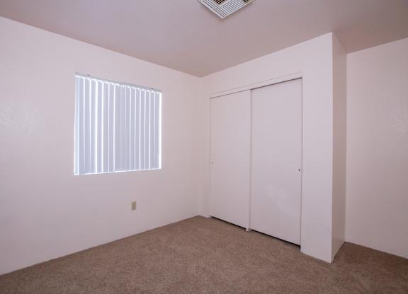 A room with a window and a closet.