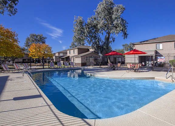 A swimming pool surrounded by trees and chairs.