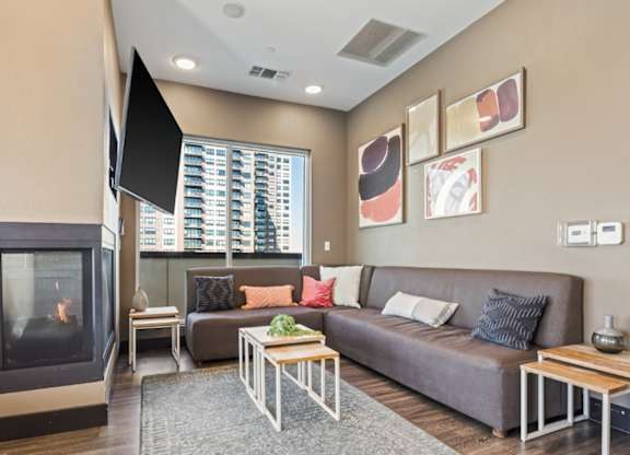 A living room with a grey couch, a fireplace, and a television.