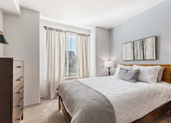 A bedroom with a large bed and a painting on the wall.
