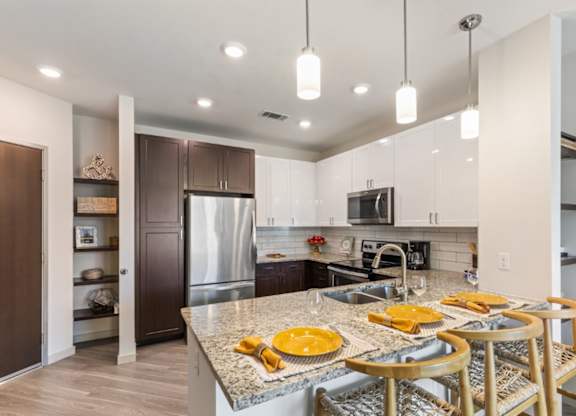 A kitchen with a marble countertop and wooden chairs.