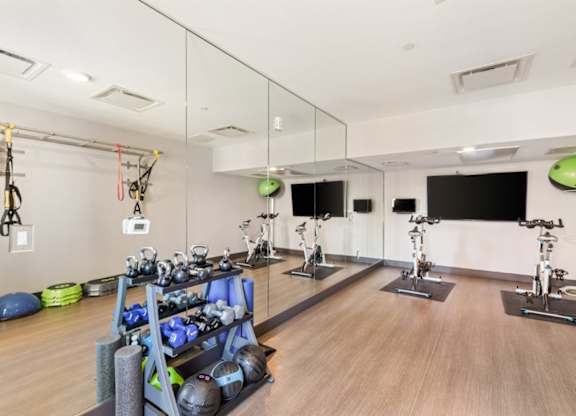 A gym with a mirrored wall and exercise equipment.