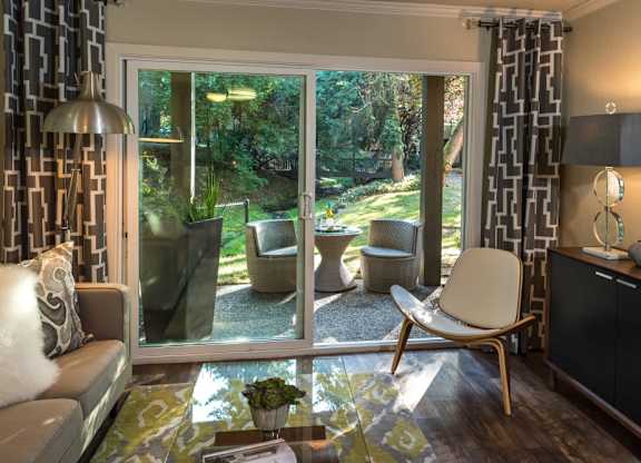 A living room with a view of a backyard through the sliding glass doors.