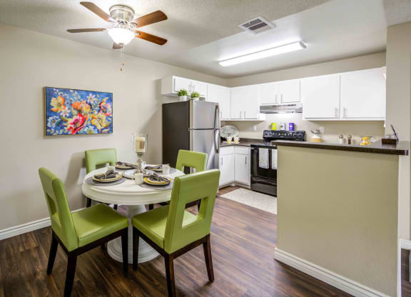 a dining room table and chairs with a kitchen in the background
