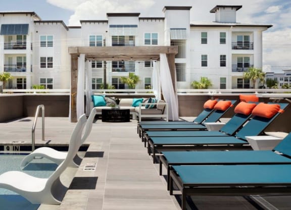 a pool with lounge chairs and a fire pit in front of an apartment building