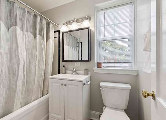 A white bathroom with a toilet, sink, and shower curtain.