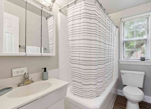 A white bathroom with a striped shower curtain.