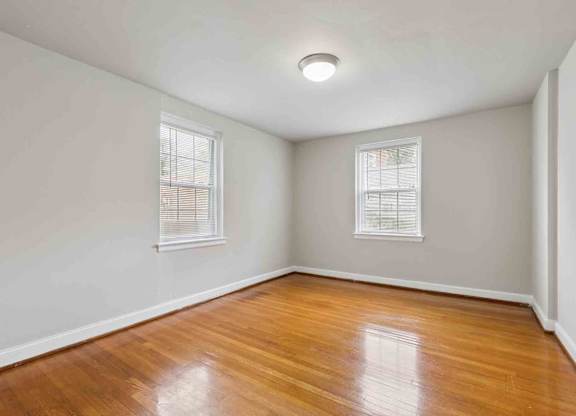 A room with wooden floors and two windows.