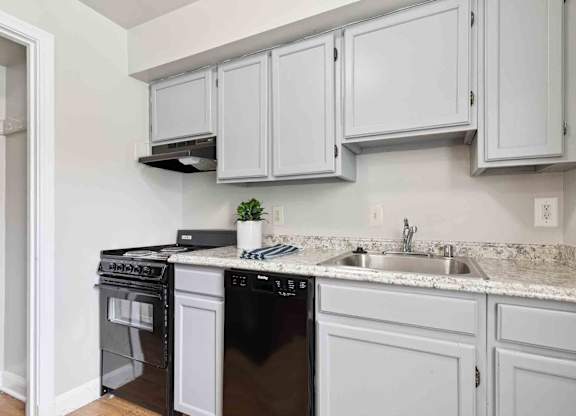A kitchen with black appliances and white cabinets.