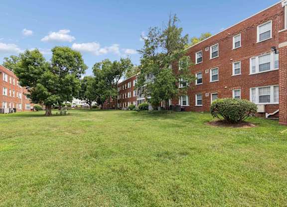 A grassy area in front of a row of red brick apartment buildings.