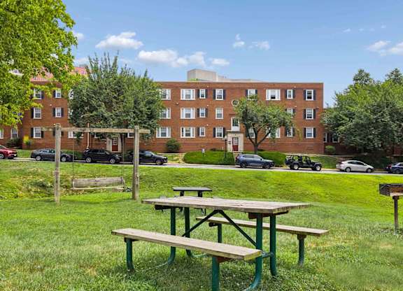 Picnic table in front of a red brick building.