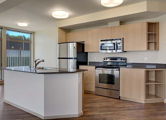 A modern kitchen with a white countertop and stainless steel appliances.