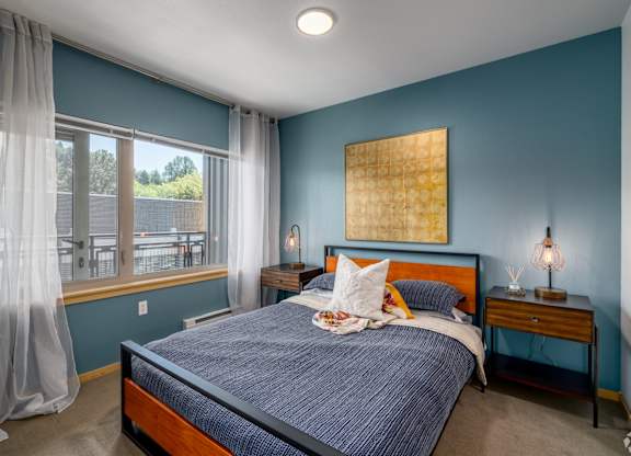 A bedroom with a bed, nightstand, and window.