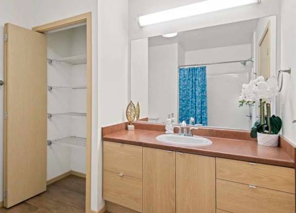 A bathroom with a sink, mirror, and a shower with a blue curtain.