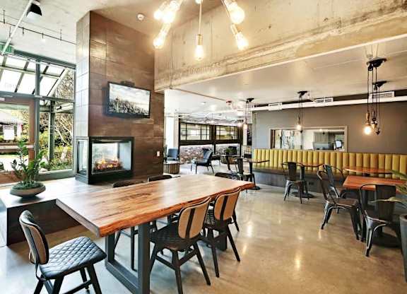 A modern dining area with a long wooden table surrounded by chairs.