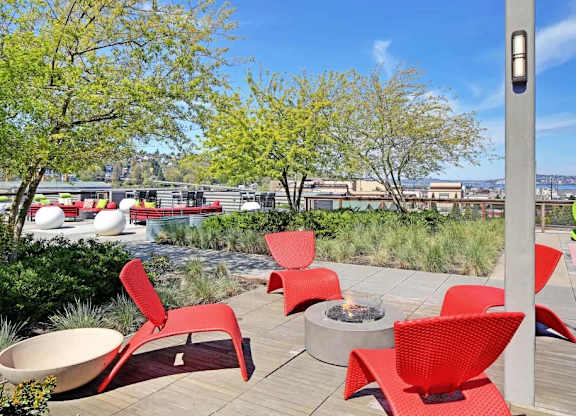 A patio with red chairs and a fire pit.