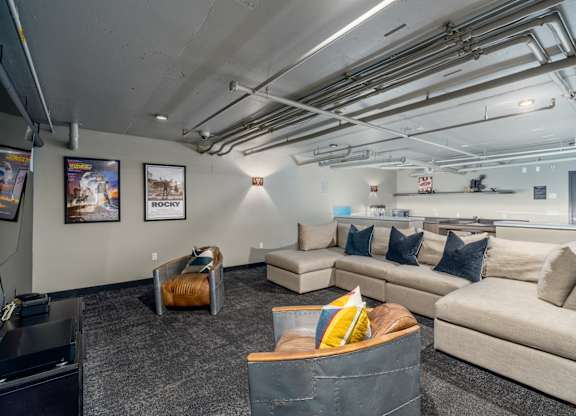 A room with a couch, chairs, and a coffee table.