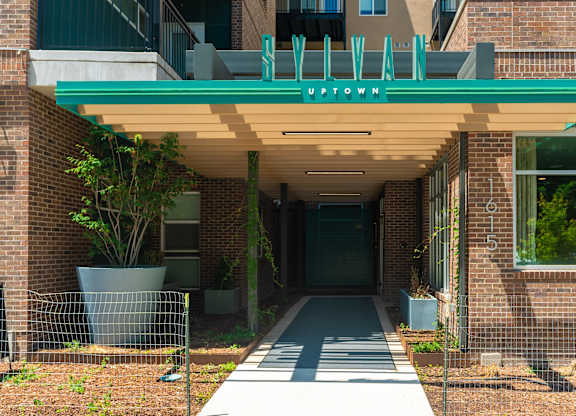 the red brick entrance to the property with a green awning at Sylvan Uptown, Denver, CO