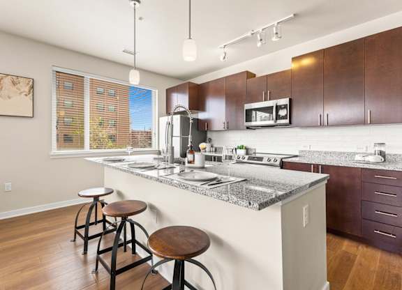View of the kitchen with a granite island with barstool seating and pendant lighting at Sylvan Uptown, Denver