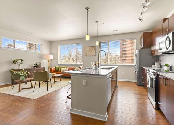 Spacious kitchen with hardwood flooring and an island with view into well-decorated living room at Sylvan Uptown, Colorado, 80203
