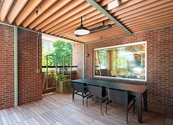Covered red brick patio with hardwood flooring, a long table and chairs at Sylvan Uptown, Denver, CO, 80203