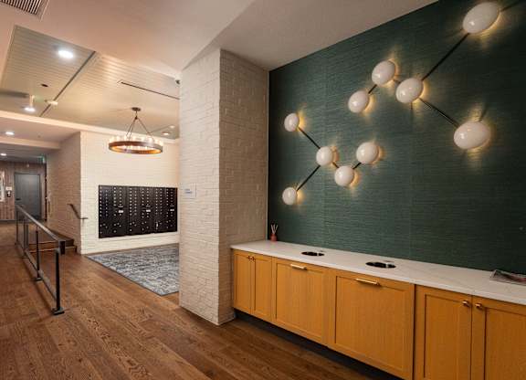 Spacious walkway to the mail area with chic wall decorations on the green wall and modern style chandelier at Sylvan Uptown, Colorado