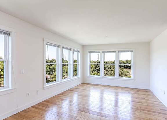 A room with wooden floors and large windows overlooking a green landscape at Park87 Apartments, Cambridge, MA