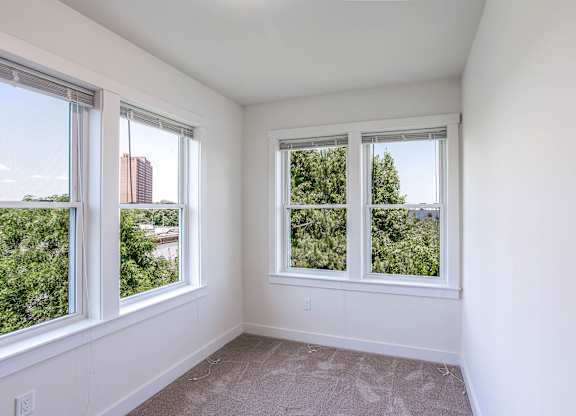 A room with two windows overlooking a cityscape and greenery at Park87 Apartments, Cambridge, Massachusetts
