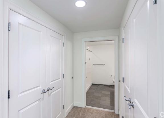 A white hallway with a door on the left and a bathroom on the right with plenty of storage at 7 Cameron Apartments, Massachusetts, 02140