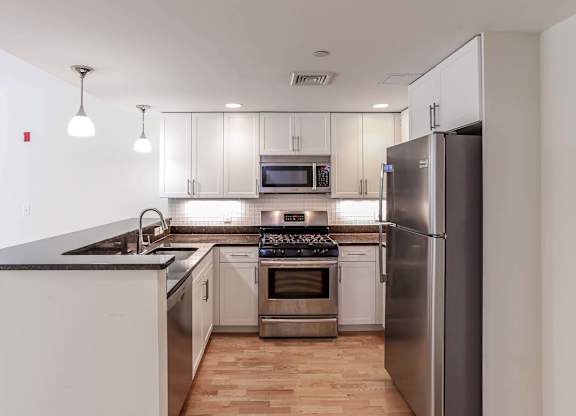 A modern kitchen with stainless steel appliances and wooden floors at 7 Cameron Apartments, Massachusetts, 02140